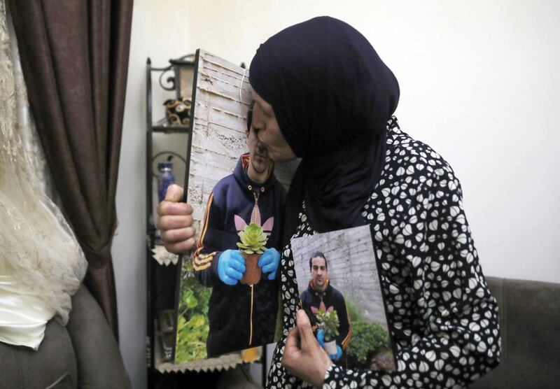 FILE - In this June 3, 2020 file photo, Rana kisses a photo of her son, Eyad Hallaq, in their home in Wadi Joz, a Palestinian neighborhood in East Jerusalem. On Wednesday, Oct. 21, 2020, Israeli prosecutors recommended charging a police officer with reckless killing in the fatal shooting of Hallaq, an autistic Palestinian man in Jerusalemâ€™s Old City earlier this year. The decision came nearly five months after the shooting and Hallaqâ€™s family condemned the decision saying police should have faced much tougher charges. (AP Photo/Mahmoud Illean, File)