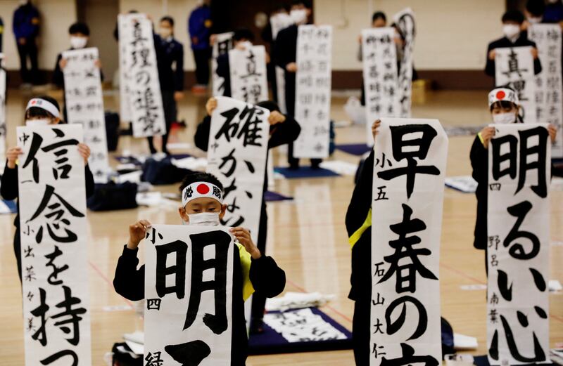 Students in Tokyo wearing masks take part in an annual New Year calligraphy contest. Last year's event was cancelled because of the pandemic. Reuters