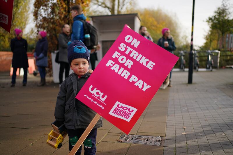 A child holds a placard as lecturers join the protest at the University of Birmingham. PA