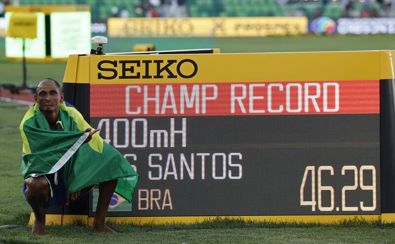 Alison Dos Santos poses next to the time board displaying his championship record at the World Athletics Championships. EPA