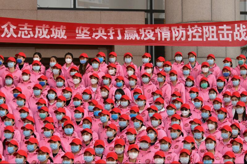 Medical workers gather near a banner that reads 'Unite as one, resolutely win the battle against epidemic' during a departure ceremony before leaving for Shanghai, in Jinan, east China's Shandong Province. AP