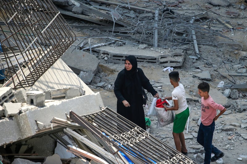 A Palestinian mother and her children inspect the rubble of their apartment at the destroyed Al Aklouk Tower following Israeli air strikes on Gaza City on Sunday. EPA