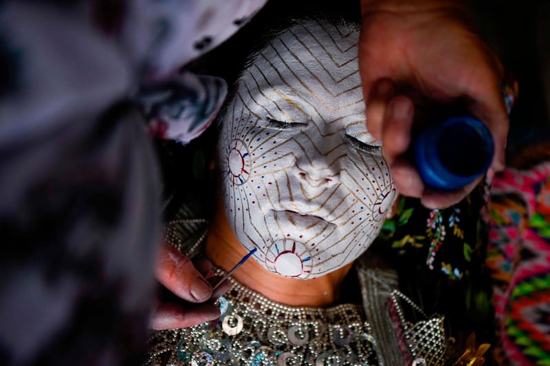 As part of the centuries old tradition, old ladies prepare young brides, painting their faces in many layers of colors while the golden circles symbolize the cycles of life. AFP