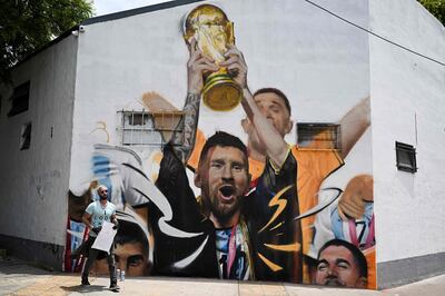 Artist Maxi Bagnasco with his mural in Buenos Aires of Lionel Messi wearing a bisht and holding the Fifa World Cup Trophy.  AFP