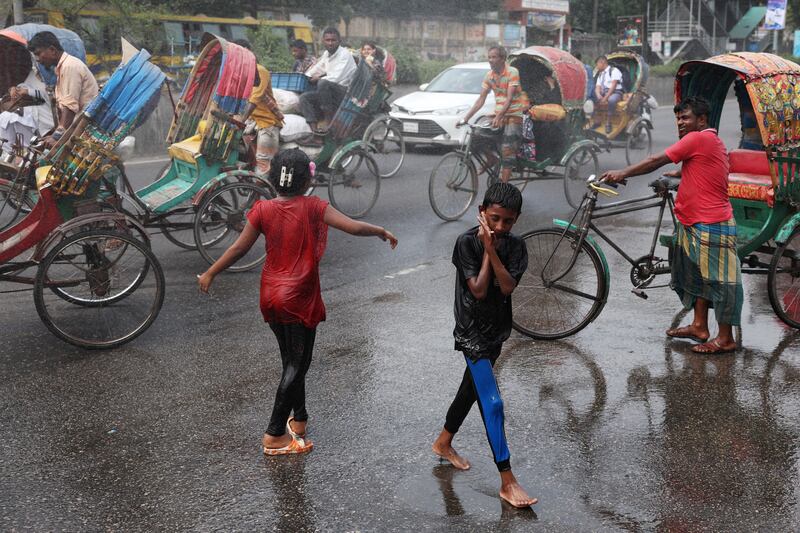 Children cool themselves in water fired from a spray cannon in Dhaka on Sunday. Reuters