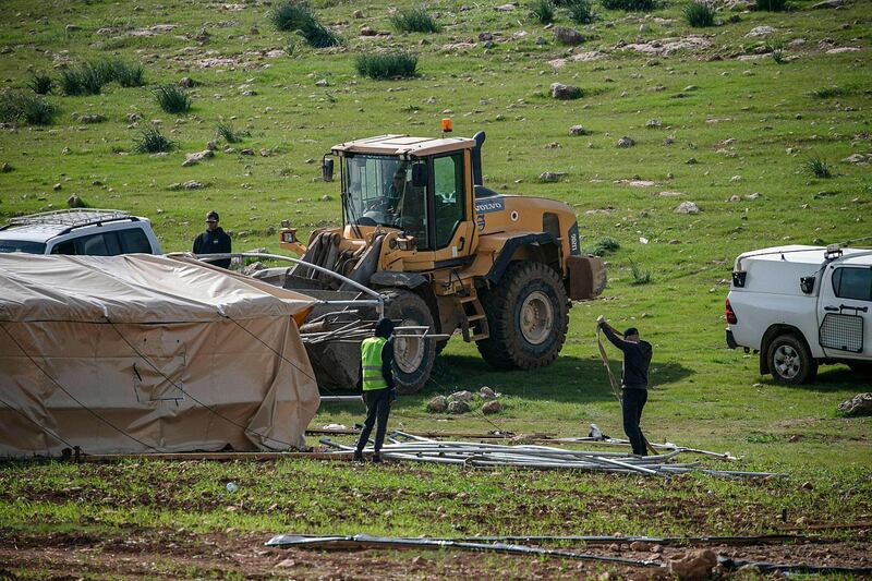 Israeli workers dismantle tents during a demolition operation of a Palestinian bedouin encampment in the area of Humsa, east of the village of Tubas in the north of the occupied West Bank on February 22, 2021.  / AFP / JAAFAR ASHTIYEH
