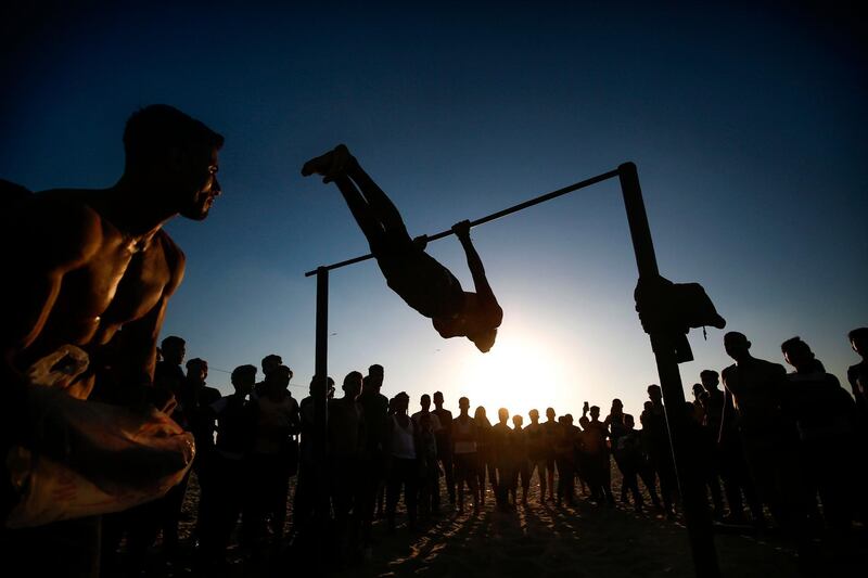A Palestinian man shows his skill on a horizontal bar at sunset on a beach in Gaza City. AFP