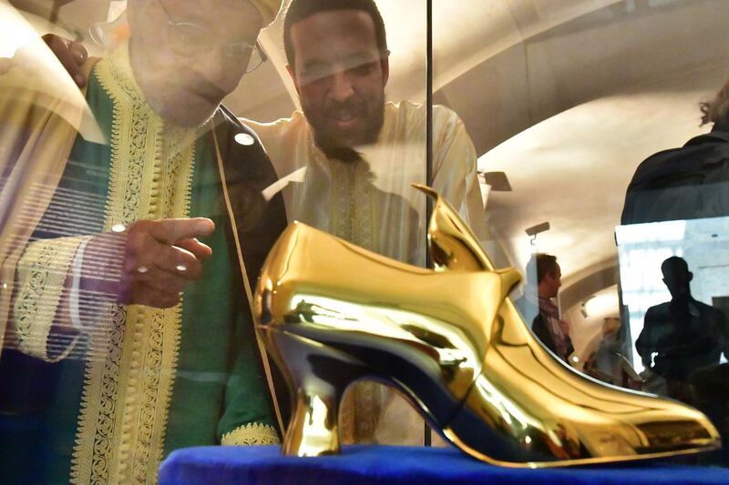 Moroccan story teller El Haj Ahmed Ezzarghani (L) looks on a golden shoe on display during a press tour at the exhibition 'Cinderella, Sindbad and Sinuhe Arab-German Storytelling Traditions' in Berlin, Germany.  EPA