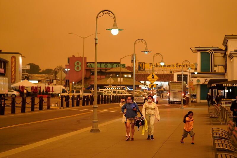 Under darkened skies from wildfire smoke, people walk at Fisherman's Wharf, in San Francisco. AP Photo
