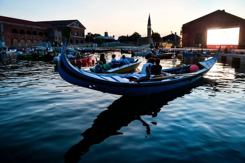 People watch from a gondola boat the film "The Prestige" directed by Christopher Nolan on the opening night of 'Barch-in', the Italy's first drive-in with boats at 'Arsenal Dock', in Venice. AFP