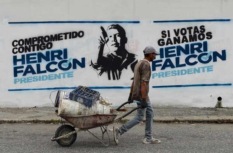 A worker passes by electoral propaganda of Venezuelan opposition presidential candidate Henri Falcon, in Barquisimeto, Venezuela, on May 19, 2018 on the eve of the country's presidential election. Venezuela holds presidential elections on May 20, in which Maduro is seeking a second six-year term.
 / AFP / Luis ROBAYO
