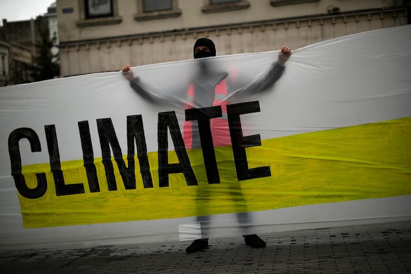 A man holds a banner with the message "United for climate" during a small climate change protest in Brussels. AP