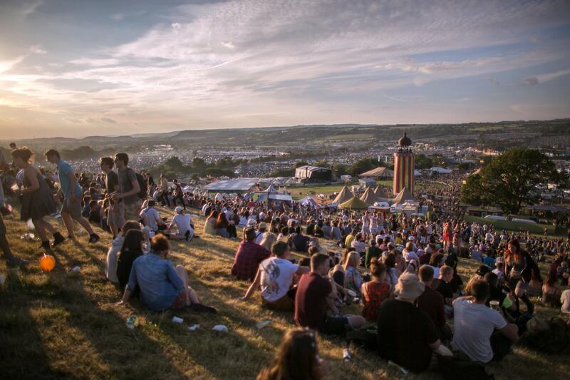 GLASTONBURY, ENGLAND - JUNE 25:  People gather to watch the sun set at Worthy Farm in Pilton on the first day of the 2014 Glastonbury Festival on June 25, 2014 in Glastonbury, England. Gates opened today at the Somerset dairy farm that plays host to one of the largest music festivals in the world. Tickets to the event, which is now in its 44th year, sold out in minutes even before any of the headline acts had been confirmed. The festival, which started in 1970 when several hundred hippies paid Â£1, now attracts more than 175,000 people.  (Photo by Matt Cardy/Getty Images)