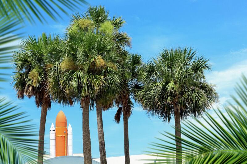 Kennedy space center entrance with space rocket and palm trees over blue sky in Florida, USA