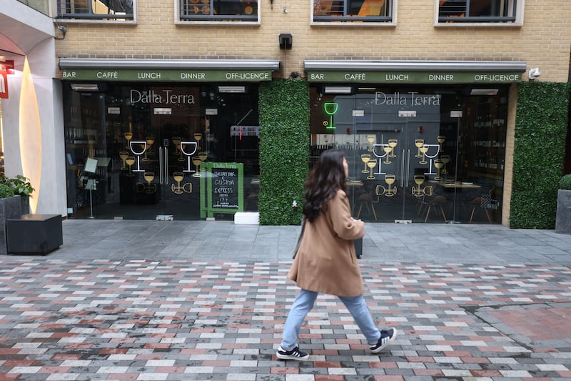 A woman passes a closed food outlet in Covent Garden, London, after a rapid rise in Covid-19 case numbers led to a surge in booking cancellations across the hospitality industry. PA