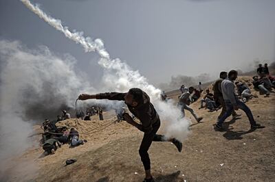epa06651640 A Palestinian protester throws back an Israeli tear-gas cannister during clashes with Israeli toops near the border with Israel in the east of Jabaliya refugee camp in the northern Gaza Strip, 06 April 2018, (issued 07 April 2018). Palestinian Islamist group Hamas called for another day of protest on 06 April, near the border with Israel, a week after 18 Palestinians were killed in clashes with Israeli forces during a march toward the border to commemorate the annual Land Day on 30 March. Protesters demanded that Palestinian refugees across the Middle East be allowed to return to their ancestral lands that are currently Israeli territory.  EPA/MOHAMMED SABER