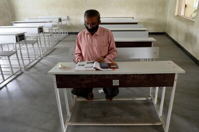 A teacher sits in an empty classroom as he prepares for online teaching at a government high school in Hyderabad on September 21, 2020, after the state government allowed 50 percent of staff at schools and colleges to resume duties for tele-counselling and online teaching amid Covid-19 coronavirus pandemic. / AFP / NOAH SEELAM
