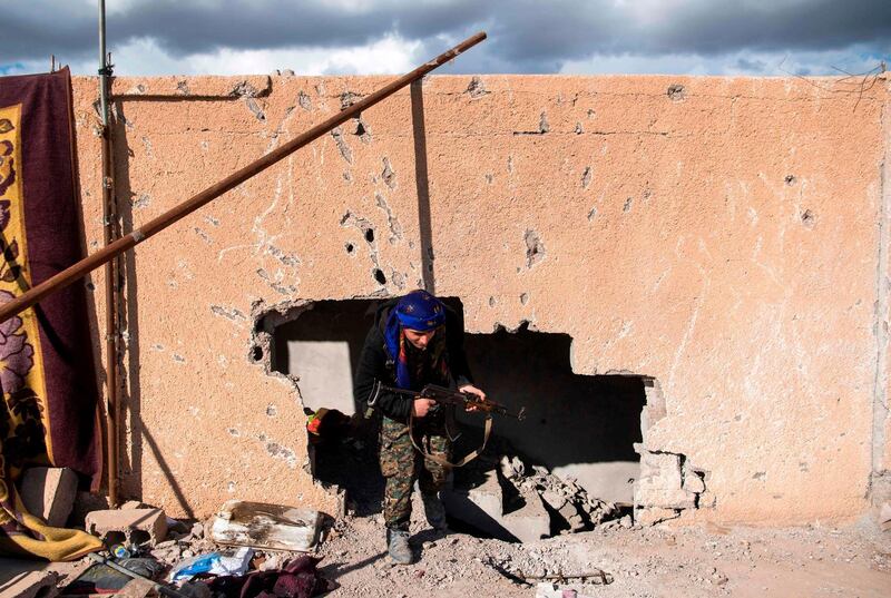 A fighter with the Syrian Democratic Forces walks through a hole in the wall in the frontline Syrian village of Baghouz. AFP