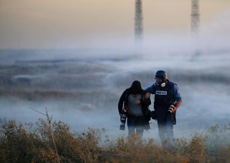 Palestinian press photographers walk amidst tear gas smoke during clashes with Israeli forces on December 11, 2017 near the border fence with Israel, east of Gaza City.
Protests flare in the Middle East and elsewhere over US President Donald Trump's declaration of Jerusalem as Israel's capital, a move that drew global condemnation and sparked days of unrest in the Palestinian territories. / AFP PHOTO / MOHAMMED ABED