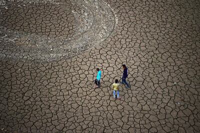 Youths walk along a dry river bed on the banks of the river Ganges, in Allahabad. AFP