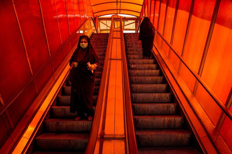 A pedestrian wears a protective face mask while travelling down a walkway escalator in Tehran, March 15. Bloomberg