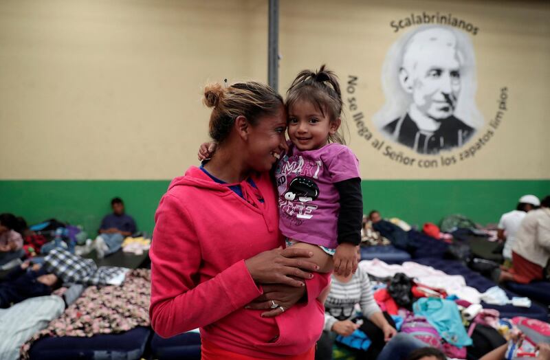 A Honduran migrant, part of a caravan trying to reach the US, carries her daughter at a migrant shelter in Guatemala City. Reuters