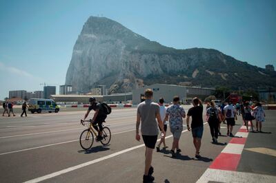 (FILES) In this file photo taken on August 15, 2019 at La Linea de la Concepcion a man rides a bicycle as people walk near the border of British Colony of Gibraltar. Spain has reached a deal with Britain to preserve freedom of movement across its border with Gibraltar just hours before the Brexit deadline expired, its top diplomat said on December 31, 2020.   / AFP / JORGE GUERRERO
