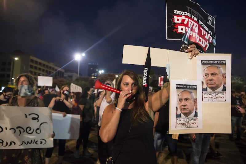 Israeli woman holds a sign with photos of Israeli Prime Minister Benjamin Netanyahu as she protests against the Government's economy response to the cororna virus crisis in Tel Aviv. Getty Images