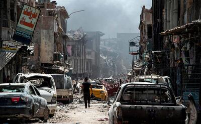 (FILES) In this file photo taken on July 02, 2017 A man walks by destroyed vehicles in a street in the Old City of Mosul on July 2, 2017, during the offensive to retake the city from Islamic State (IS) group fighters. Iraqi forces announced the "liberation" of the country's second city on July 10, 2017, after a bloody nine-month offensive to end the Islamic State (IS) group's three-year rule there. 
Scores of people are still displaced in and around Mosul as the city lies in ruins, one year after it was retaken from IS. 

 / AFP / Fadel SENNA
