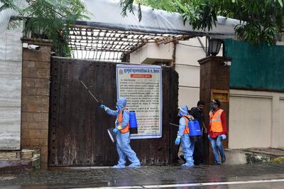 Civic authority workers spray sanitiser on the main door of the residence of Bollywood star Amitabh Bachchan as he tested positive for COVID-19 in Mumbai on July 12, 2020. Bollywood megastar Amitabh Bachchan, 77, tested positive for COVID-19 on July 11 and was admitted to hospital in Mumbai, with his actor son Abhishek -- who also announced he had the virus -- saying both cases were mild. / AFP / Sujit Jaiswal
