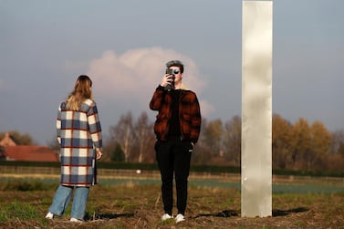 People take photos in front of a metal monolith in a field in Baasrode, Belgium, on Tuesday, December 8. EPA