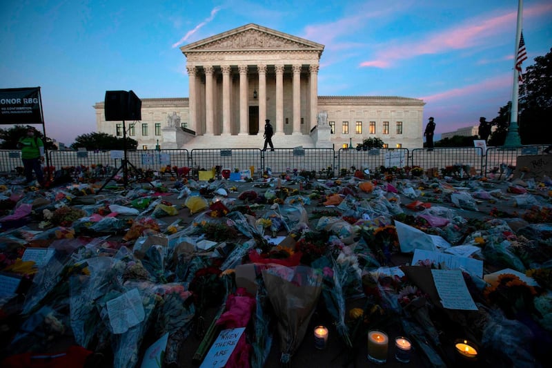 Flowers, candles, and signs are pictured at a makeshift memorial outside of the US Supreme Court as people pay their respects to Ruth Bader Ginsburg in Washington, DC on September 19, 2020. US President Donald Trump vowed to quickly nominate a successor, likely a woman, to replace late Supreme Court Justice Ruth Bader Ginsburg, only a day after the death of the liberal stalwart. / AFP / Jose Luis Magana
