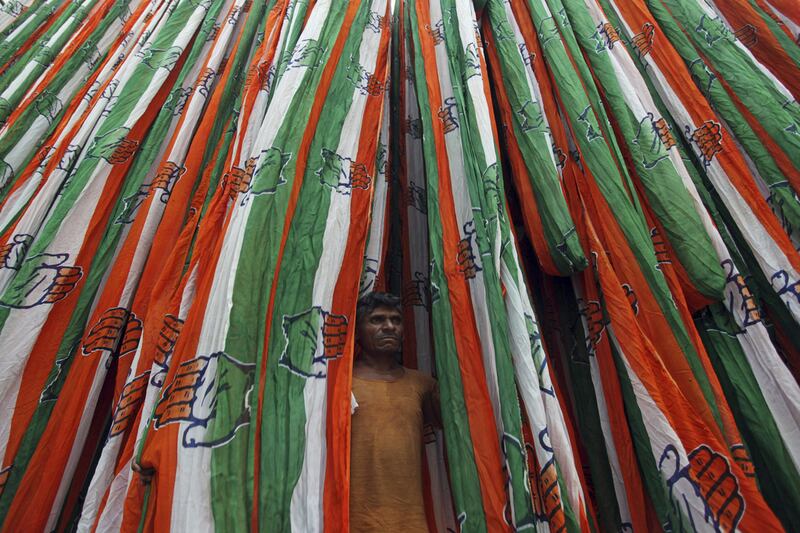 An Indian worker stands in between lengths of cloth with the party symbol of India’s ruling Congress party to be used as election paraphernalia in Ahmadabad. Ajit Solanki / AP Photo