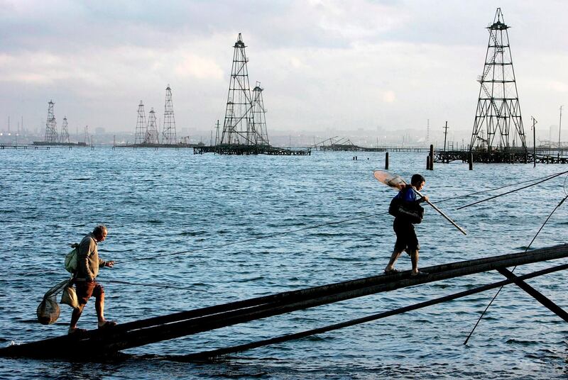 epa06945531 (FILE) - Two sailors walk in front of the oil derricks on the Caspian Sea near Baku, Azerbaijan, 07 October 2005 (reissued 12 August 2018). The leaders of five countries bordering the Caspian Sea - Caspian Five Russia, Iran, Kazakhstan, Azerbaijan and Turkmenistan - plan tosign the Convention of the legal status of the Caspian Sea at the Aktau summit on 12 August. It is expected to clarify the resources-rich Caspian Sea's status of whether being a lake or a sea, and ban non-littoral states from mliitary presence in the world's largest enclosed inland body of water.  EPA/SERGEI ILNITSKY *** Local Caption *** 00546820