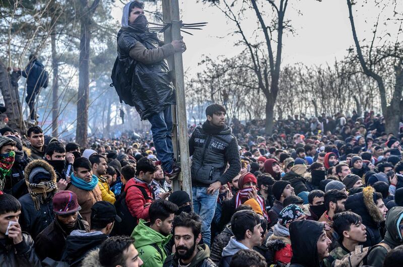 TOPSHOT - Migrants gather inside the buffer zone of the Turkey-Greece border, at Pazarkule, in Edirne district, on February 29, 2020. Thousands of migrants stuck on the Turkey-Greece border clashed with Greek police on February 29, 2020, according to an AFP photographer at the scene. Greek police fired tear gas at migrants who have amassed at a border crossing in the western Turkish province of Edirne, some of whom responded by hurling stones at the officers. The clashes come as Greece bolsters its border after Ankara said it would no longer prevent refugees from crossing into Europe following the death of 33 Turkish troops in northern Syria. / AFP / BULENT KILIC
