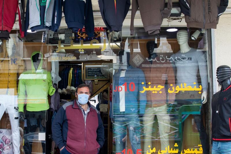 A clothes shop owner wearing a protective faced mask is waiting for customers in Downtown Amman. EPA