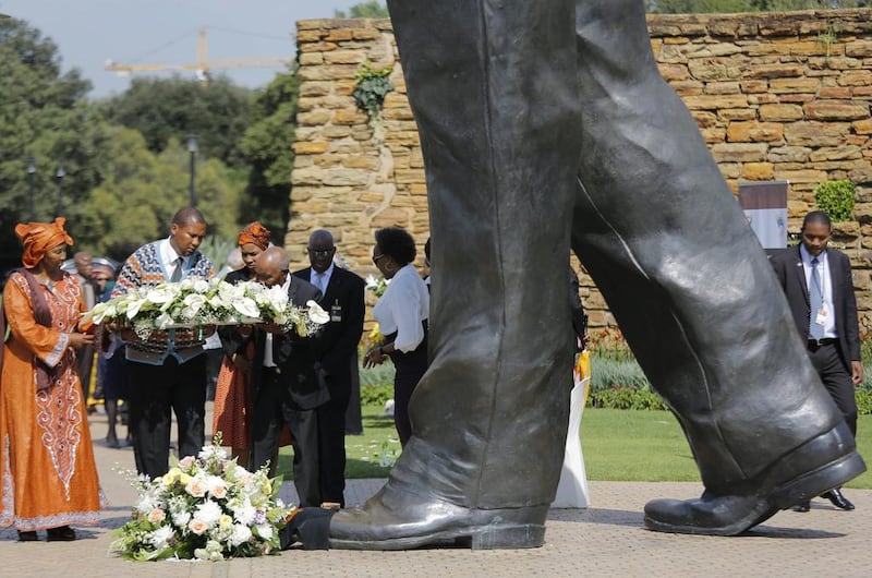 Nelson Mandela’s grandson, Mandla Mandela, second left, lays flowers at the feet of a huge statue during a memorial in Pretoria.  Kim Ludrook / EPA