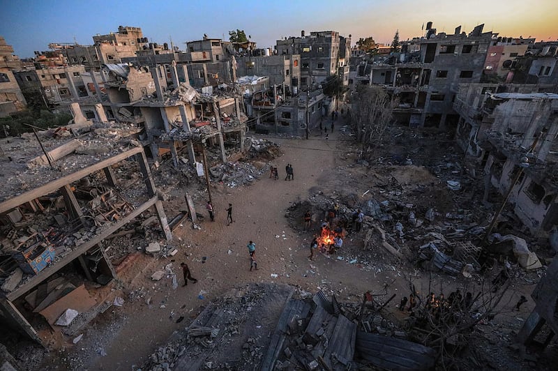 Palestinians gather round a fire between their destroyed homes in Beit Hanoun in the northern Gaza Strip.  EPA