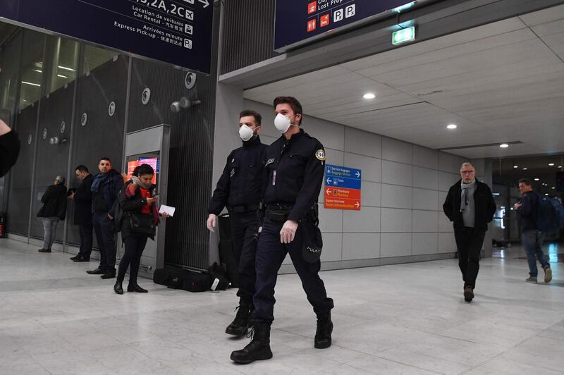 Policemen wearing protection masks patrol in the arrival Terminal in Charles De Gaulle Airport on January 26, 2020. / AFP / Alain JOCARD
