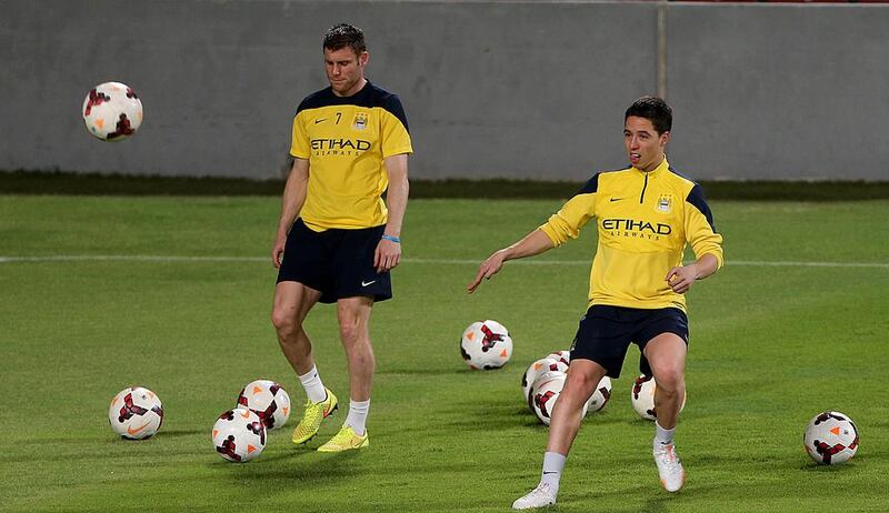 Samir Nasri, right, sends a cross with James Milner, left, nearby, during a drill at Manchester City's training session in Abu Dhabi on Wednesday night. Satish Kumar / The National / May 14, 2014