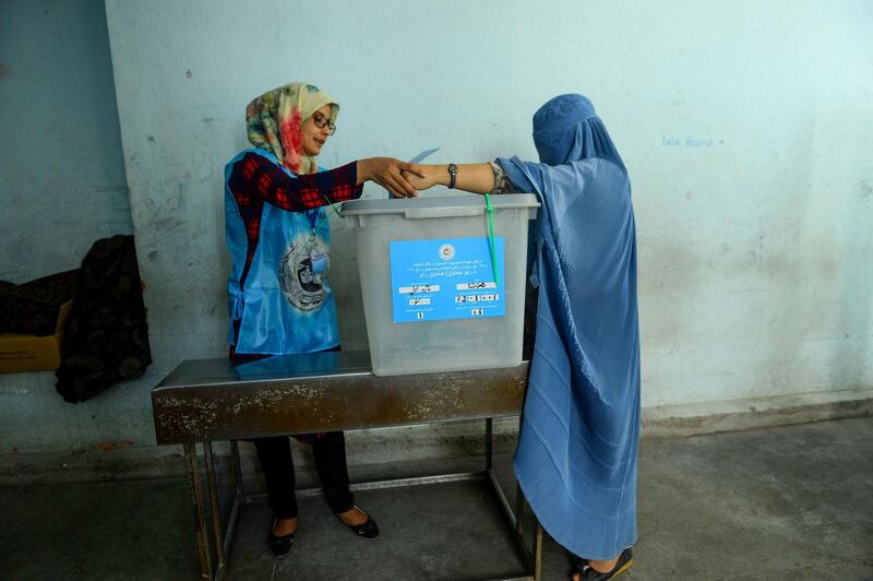 An Independent Election Commission (IEC) official helps a woman to cast her vote at a polling station in Herat. AFP