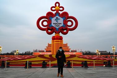 A man walks past an installation displaying a Chinese knot with the logo of the Beijing 2022 Winter Olympics at Tiananmen Square in Beijing on January 19, 2022.  (Photo by JADE GAO  /  AFP)