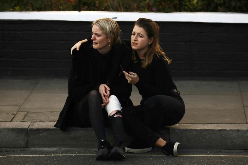 An injured woman is comforted outside Parsons Green tube station in London. Kevin Coombs / Reuters