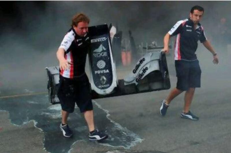 Racing team crews carry the front end of a car after a fire in the Williams racing pit stand at the Circuit de Catalunya on May , 2012 in Montmelo on the outskirts of Barcelona after the Spanish Formula One Grand Prix. AFP PHOTO / DIMITAR DILKOFF  *** Local Caption *** 507874-01-08.jpg