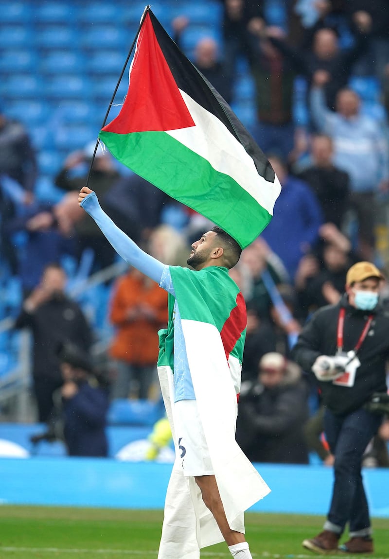 Riyad Mahrez waves a Palestine flag after Manchester City ended their title-winning season with a 5-0 win over Everton at the Etihad Stadium on Sunday, May 23, 2021. PA