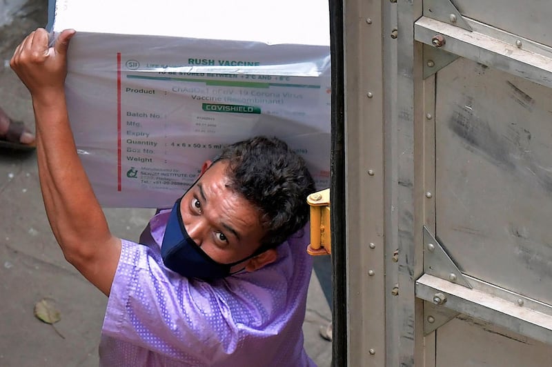 Workers transfer carton boxes of a Covishield vaccine developed by Pune based Serum Institute of India (SII) that arrived in a truck into the Karnataka Health Department cold storage facility in Bangalore on January 12, 2021, in preparation for the first round of vaccination drive scheduled to begin across the country from January 16. / AFP / Manjunath Kiran
