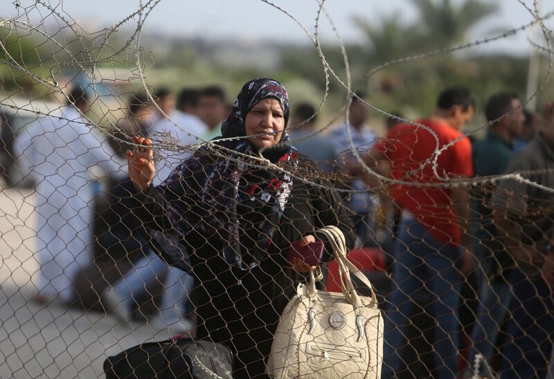 A Palestinian woman stands by a fence as she waits for a travel permit to cross into Egypt through the Rafah border crossing after it was opened by Egyptian authorities for humanitarian cases, in Rafah in the southern Gaza Strip August 16, 2017. Ibraheem Abu Mustafa / Reuters