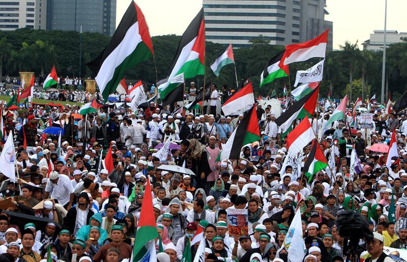 epa06394628 Indonesian muslim activists hold placards and wave Palestine national flags during a protest against US President Donald J.Trump's decision to recognize Jerusalem as capital of Israel at the National Mounement in Jakarta, Indonesia, 17 December 2017. On 06 December, US president Donald J. Trump announced he is recognising Jerusalem as the capital of Israel and will relocate the US embassy from Tel Aviv to Jerusalem.  EPA/ADI WEDA