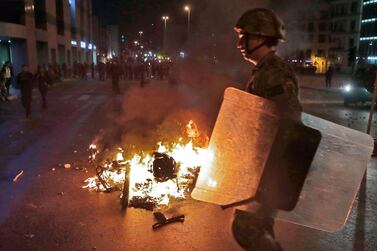 A Lebanese army soldier walks near a burning motorcycle amid clashes between supporters of the Shiite Hezbollah and Amal groups, and anti-government protesters in the capital Beirut. AFP