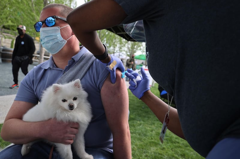 A man holds his emotional support dog, Rhea, as he receives a dose of the Johnson & Johnson coronavirus vaccine during a walk-up clinic at the Kennedy Centre's outdoor Reach area in Washington, DC. AFP